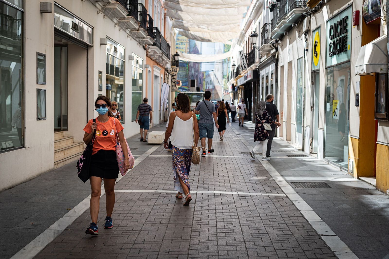 Varias personas pasean por una calle comercial de la capital onubense.