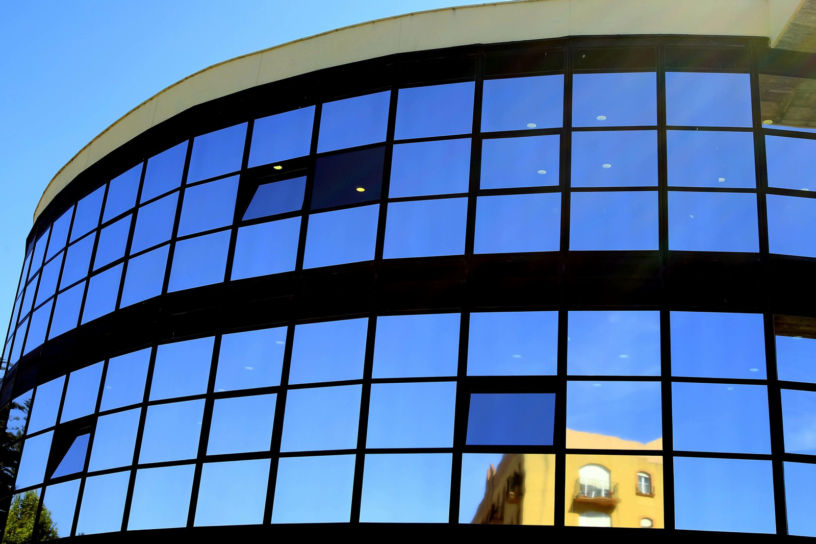 Un edificio  de viviendas se refleja en la pared acristalada de la fachada del Ayuntamiento  de La Línea