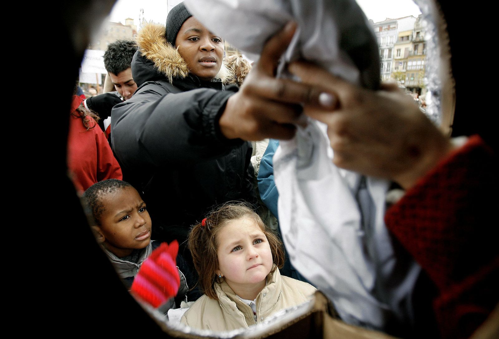 Una mujer deposita en una gran lavadora simulada en Pamplona una prenda escrita con una causa que a su entender provoca la pobreza  en el mundo.