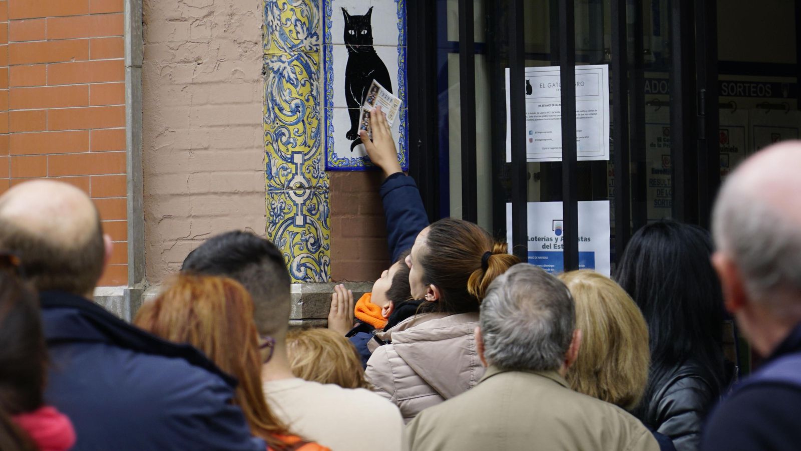 Un niño frota los décimos en el gato negro, tal como dice la tradición.