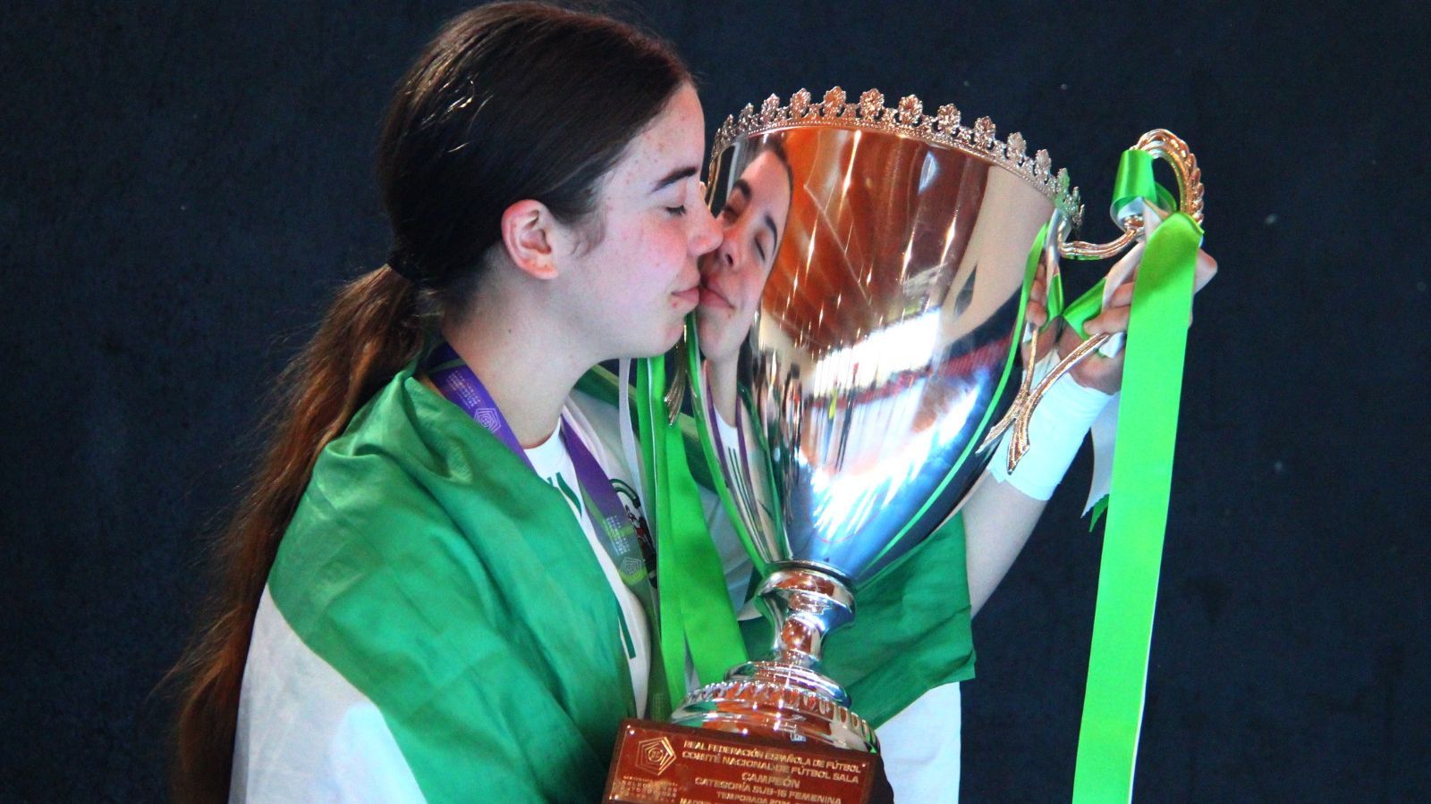 Crala Sánchez besa la copa de campeona de España envuelta en una bandera de Andalucía.