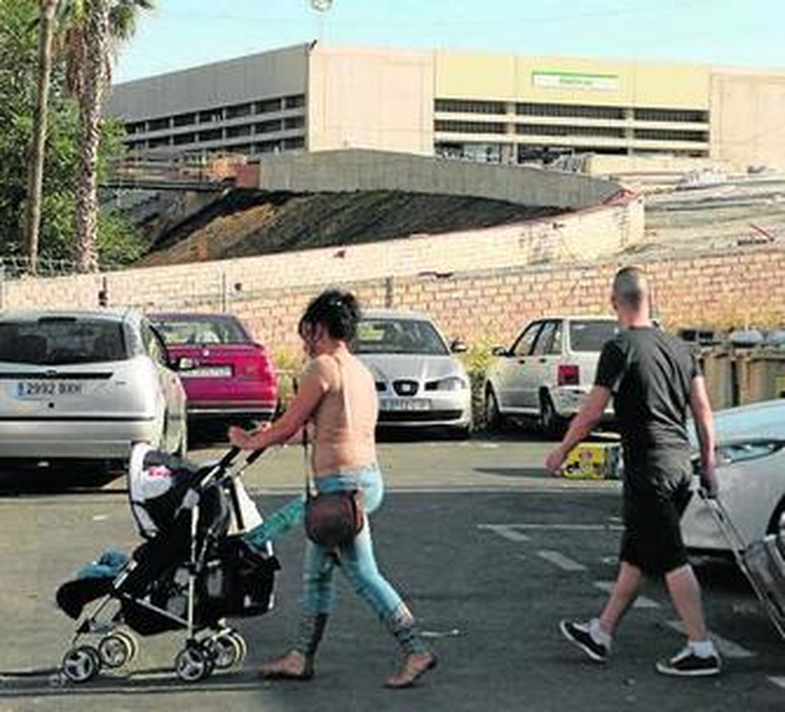 1. Una persona mayor sube con ayuda de su bastón la rampa provisional de obra que conduce a la entrada de la estación Cocheras del Metro 2. Exterior de la estación, la única en  obras y la más elevada de la capital 3. Restos de suciedad en los alrededores y, al fondo, el parque que completa la reurbanización.