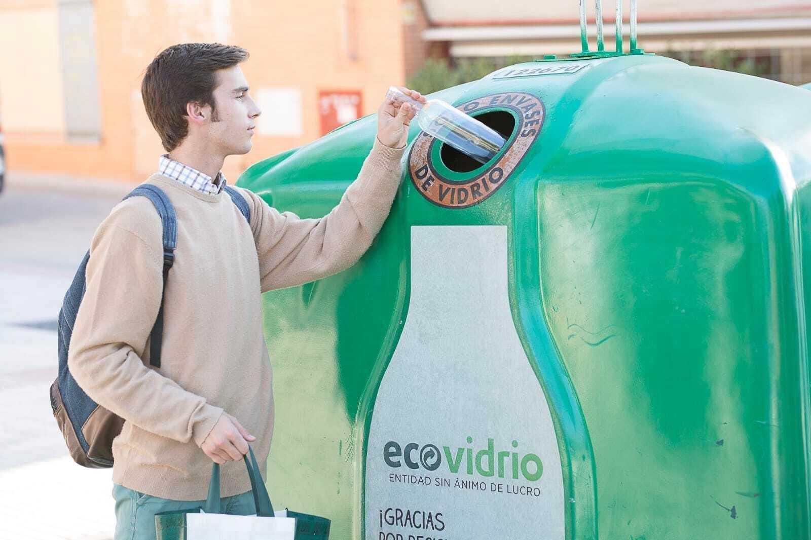 Un ciudadano deposita un vidrio en el contenedor verde.