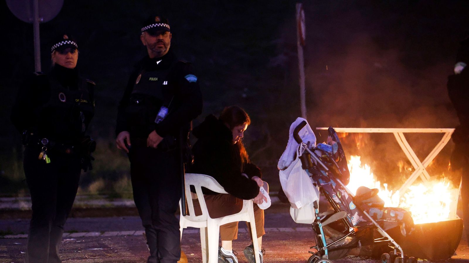 Dos agentes de la Policía Local, junto a una candela en el barrio Guadalquivir.