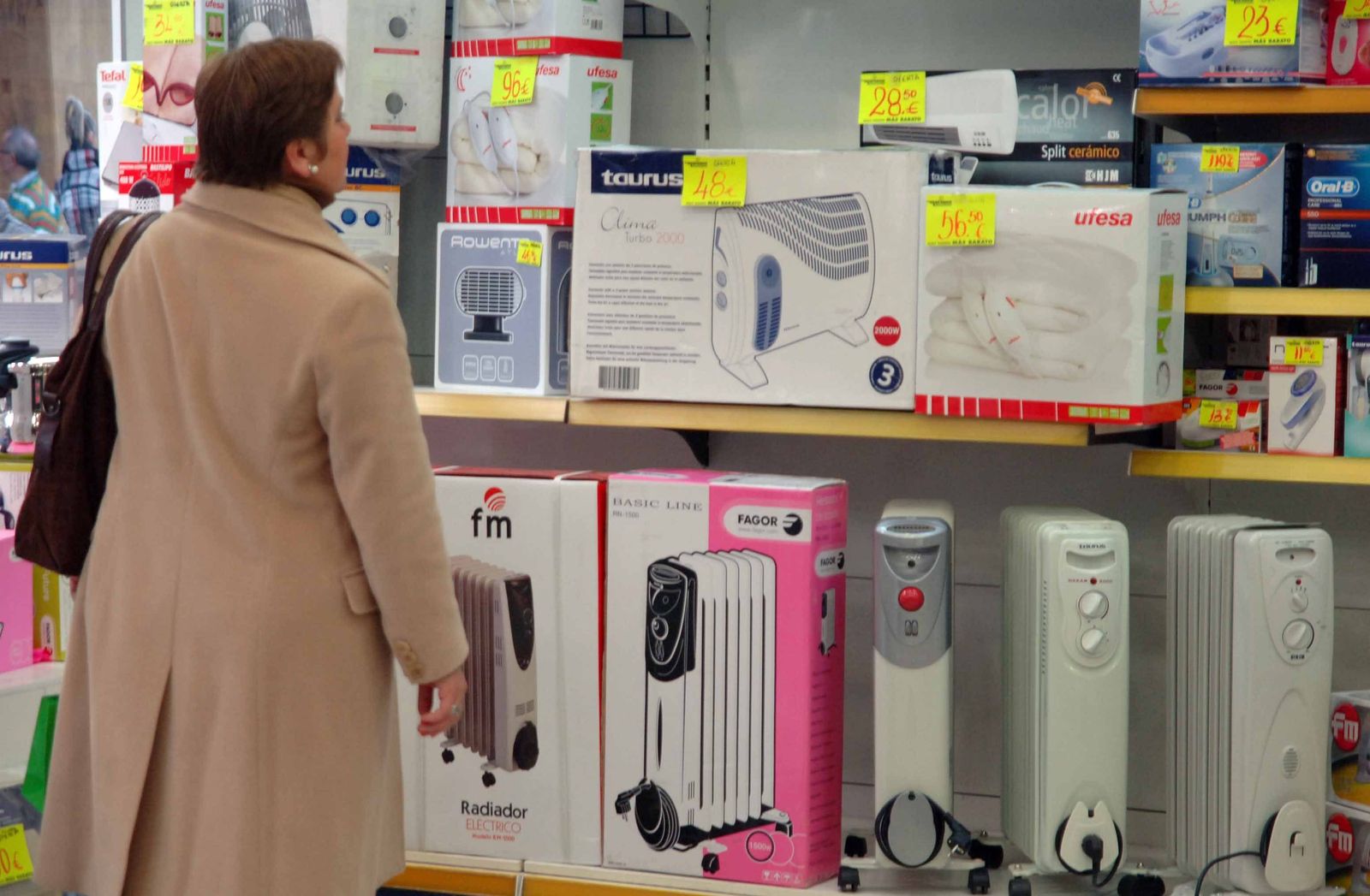 Una mujer observa los diferentes tipos de estufas y calentadores en una tienda de electrodomésticos.