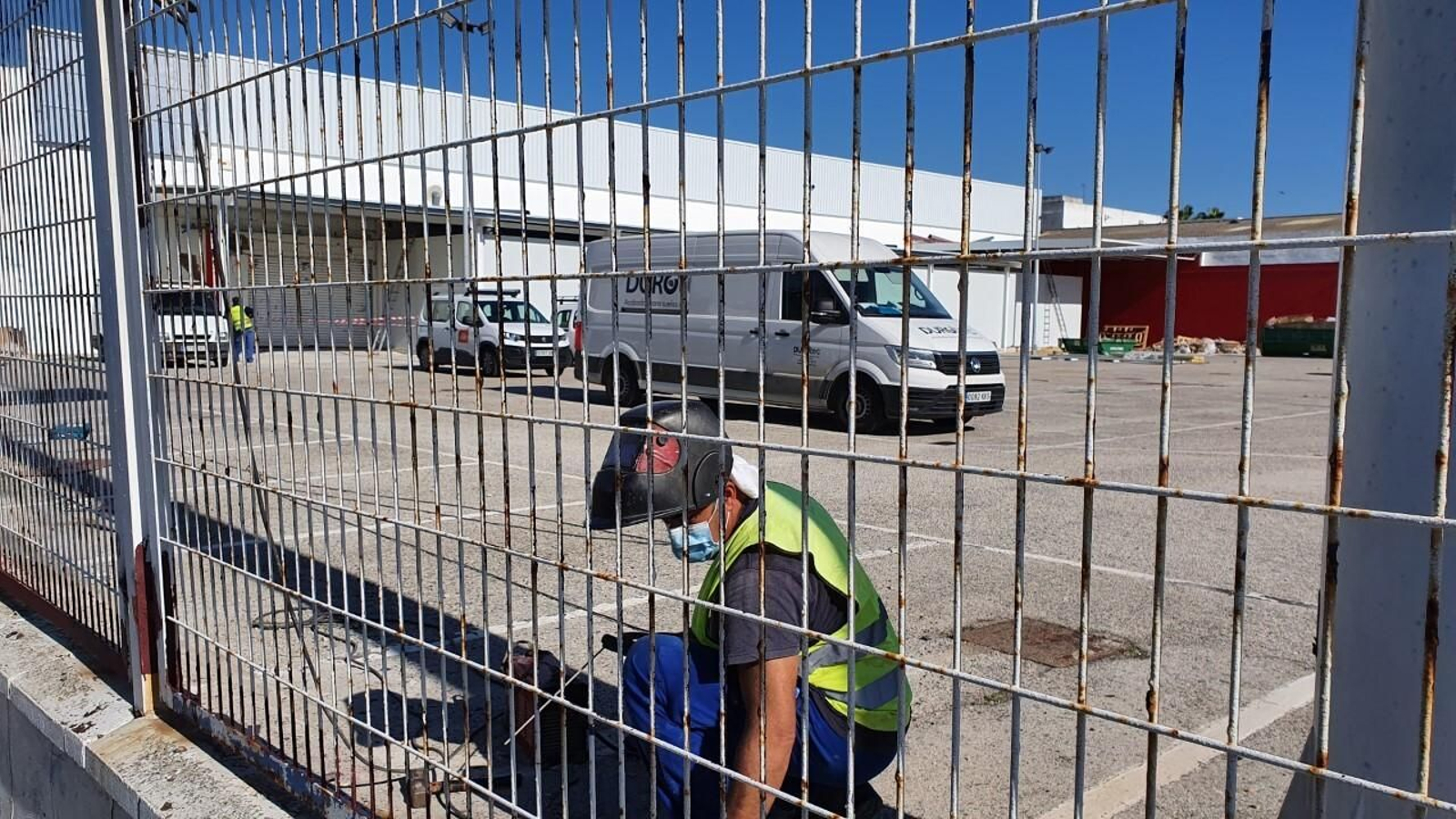 Imagen de esta misma mañana en la que se ve a un obrero reparando la valla de supermercado.
