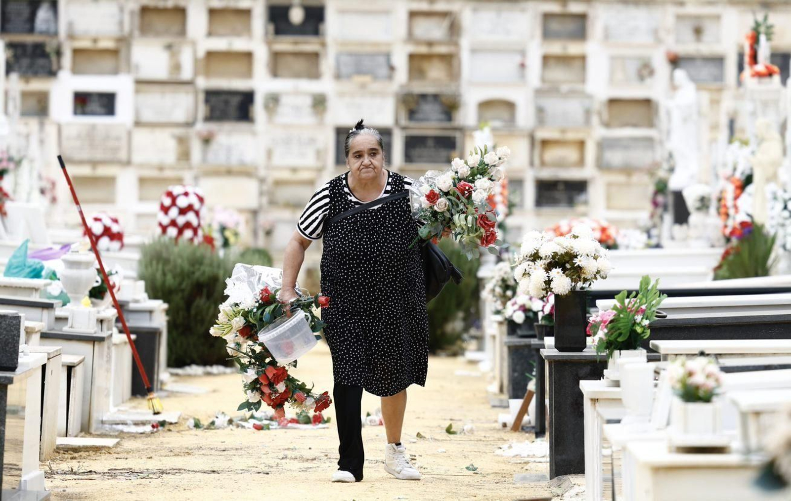 Una mujer le lleva un ramo de flores a un difunto en el cementerio de Sevilla.