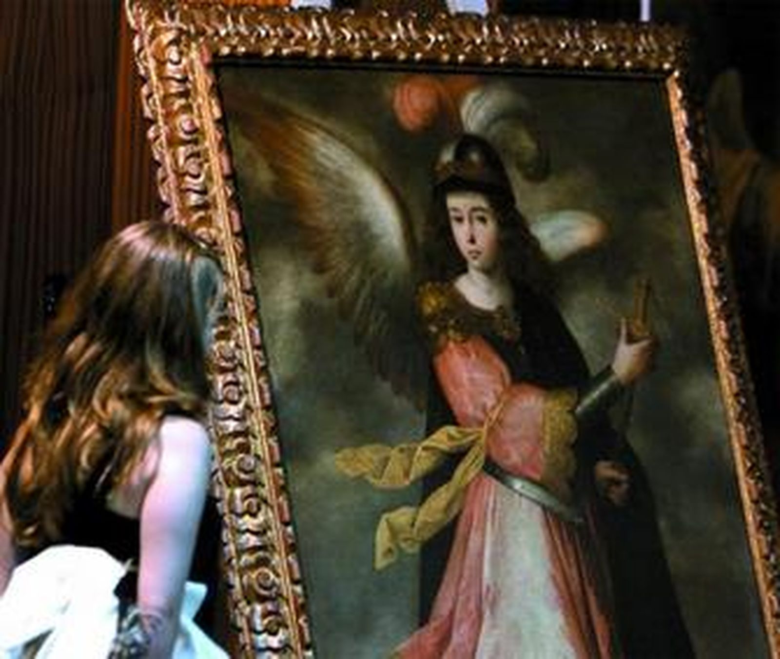 Una joven observa una de las obras pertenecientes a la escuela de Zurbarán recuperada por la Policía.