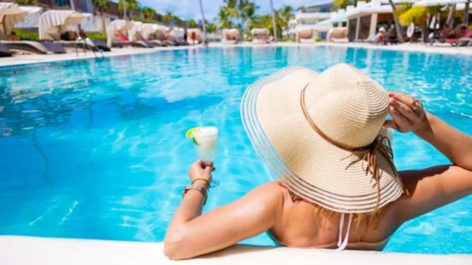 Mujer en una piscina con una bebida. Mujer en una piscina con una bebida.