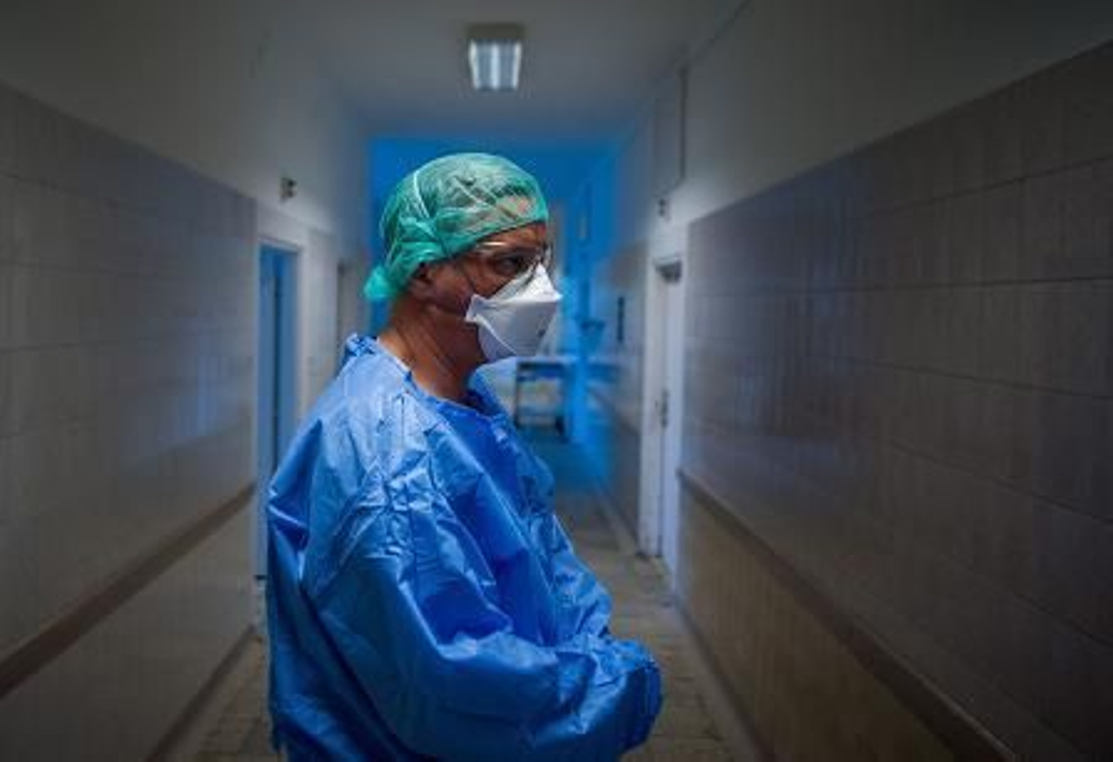 Un médico espera en un pasillo protegido con mascarilla. Un médico espera en un pasillo protegido con mascarilla.
