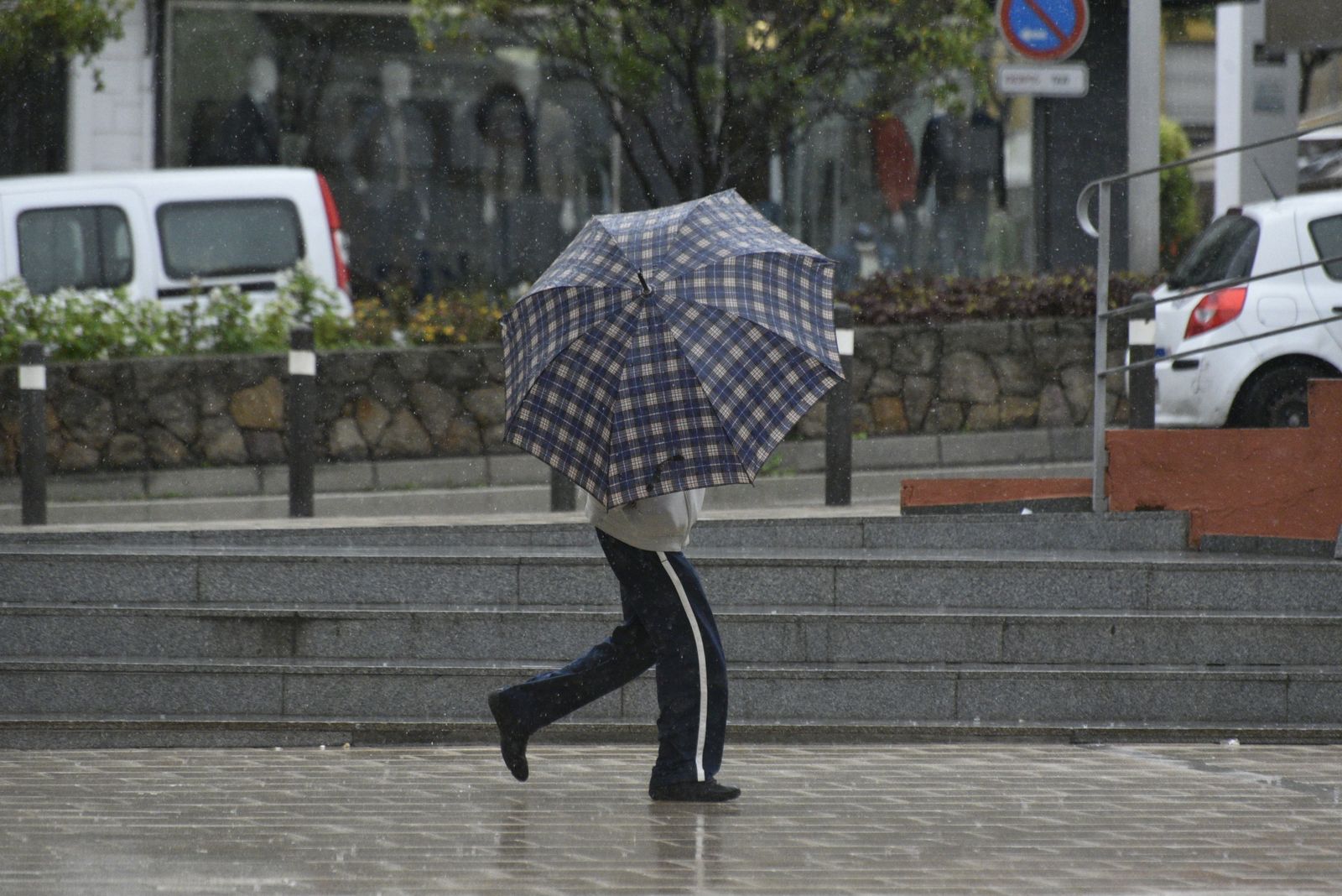 Un hombre camina con un paraguas por el centro de Algeciras.