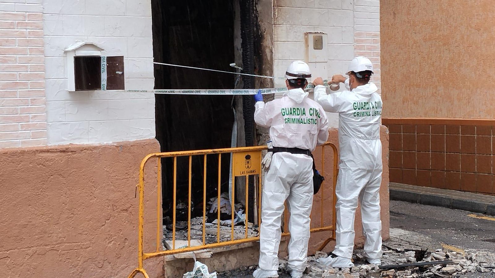 Agentes de la Guardia Civil precintan la puerta de entrada a la casa incendiada