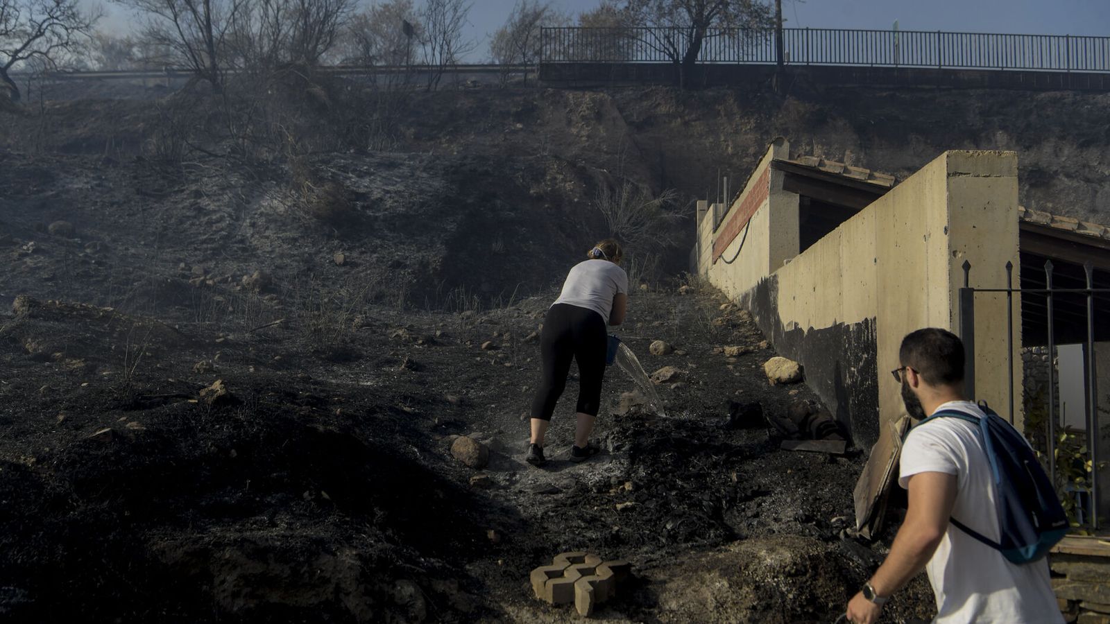 Varios vecinos echan agua para refrescar el suelo quemado en Huétor Santillán