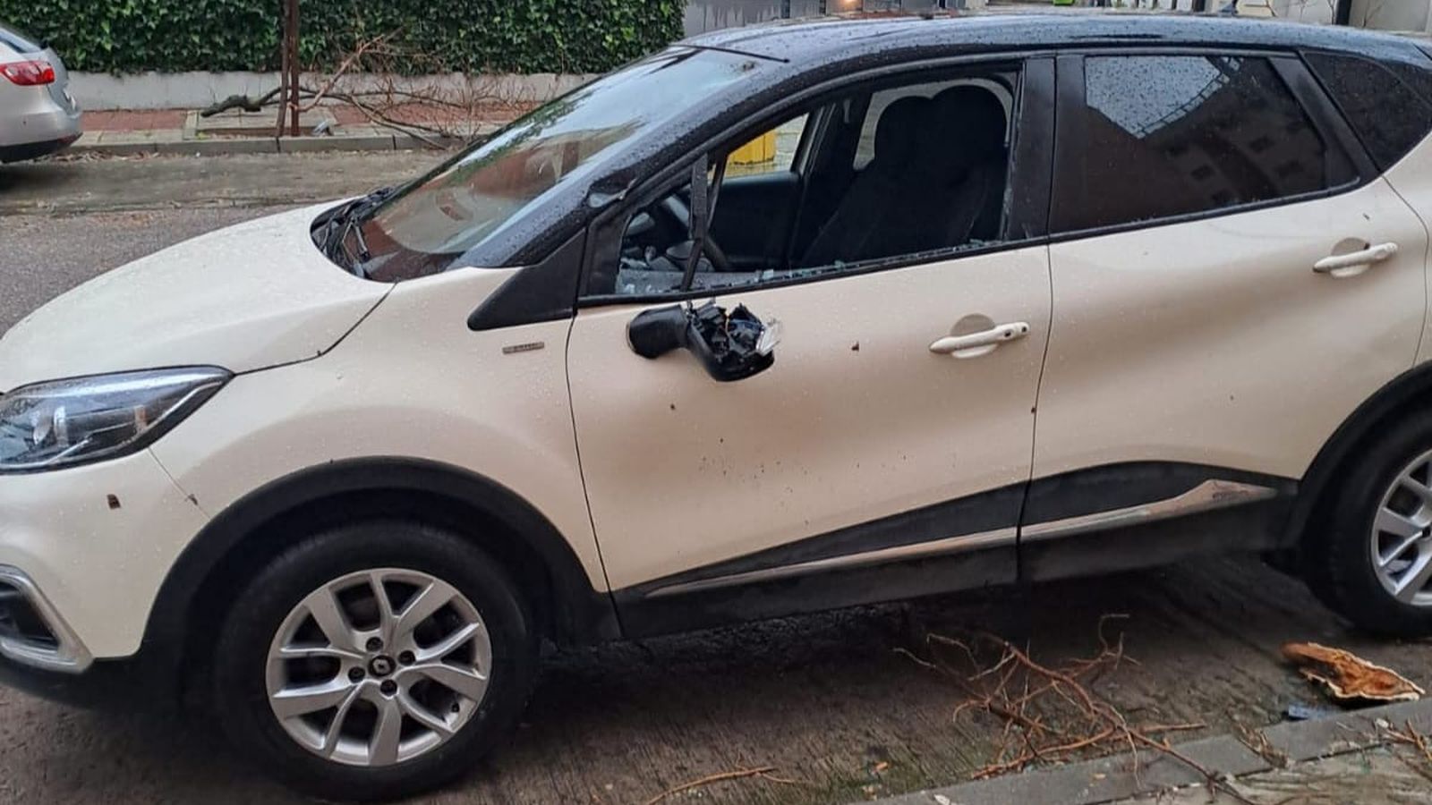 Un coche con el espejo retrovisor y una ventana rota a causa de la caída de un árbol, en Mairena del Aljarafe.