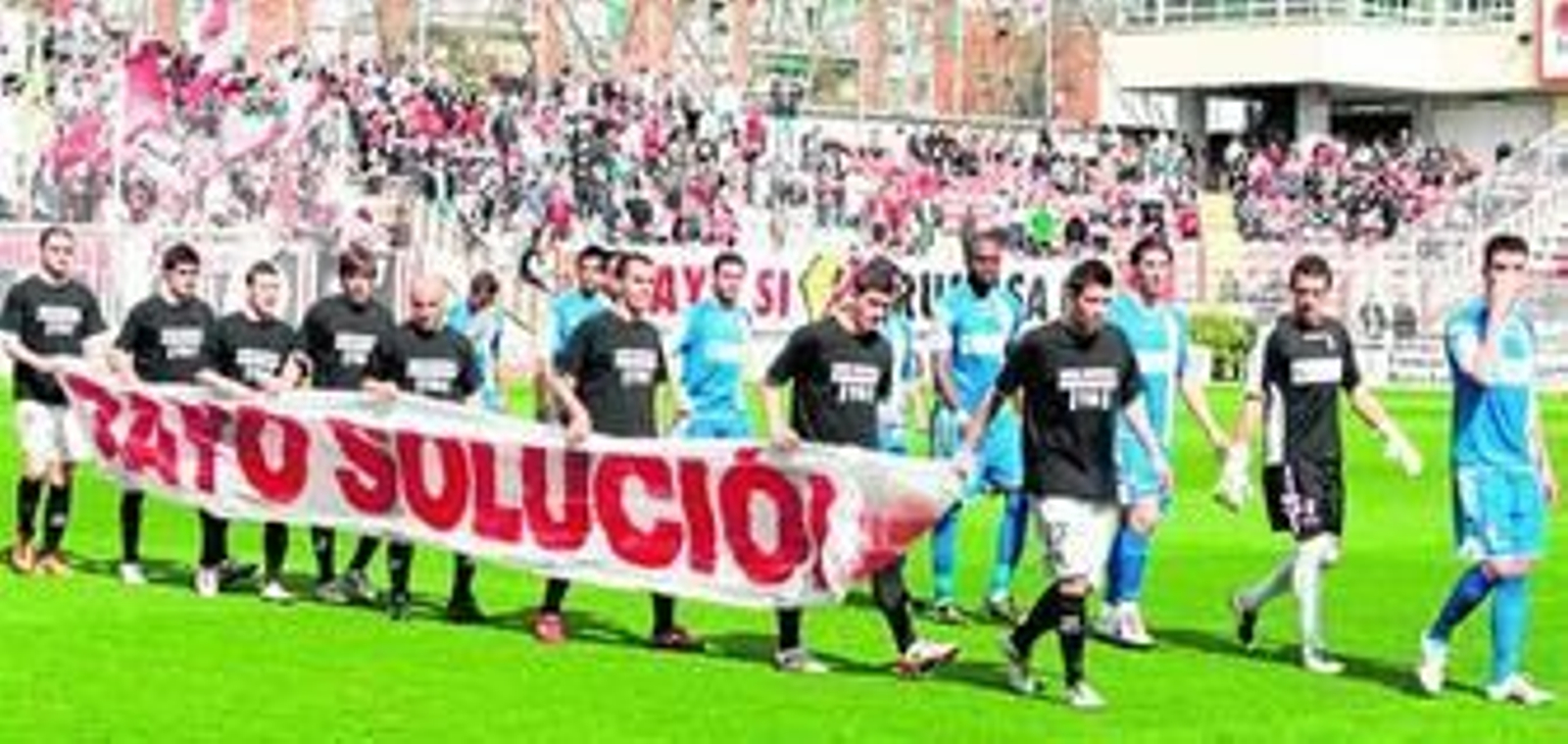 Los jugadores del Rayo Vallecano portaron una pancarta cuando saltaron al campo para pedir una solución a sus problemas económicos.