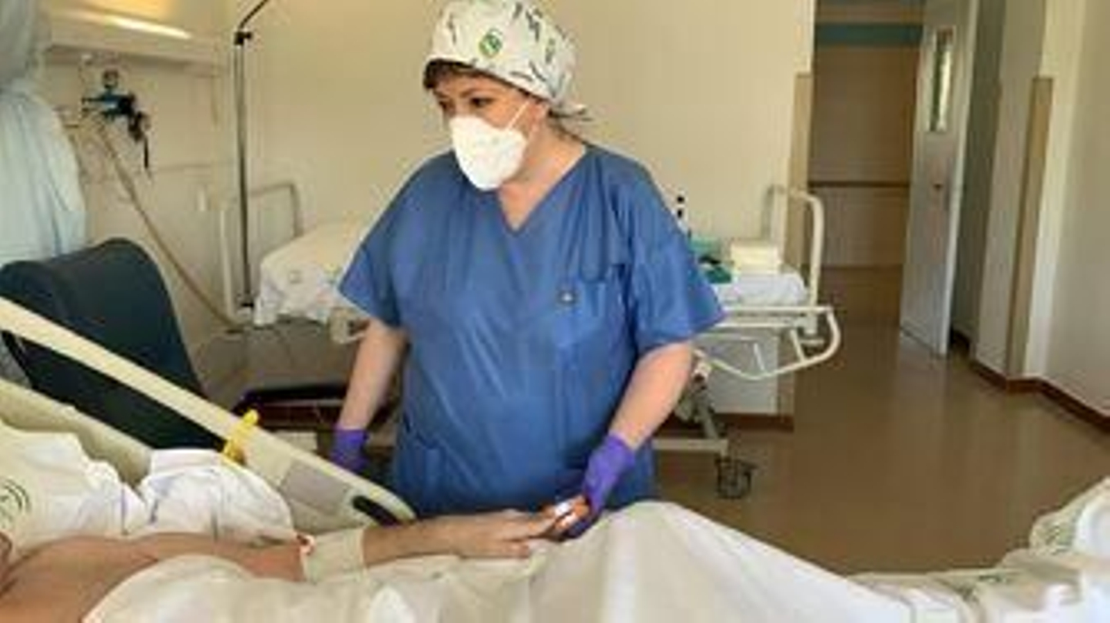 Una sanitaria asiste a un paciente hospitalizado.