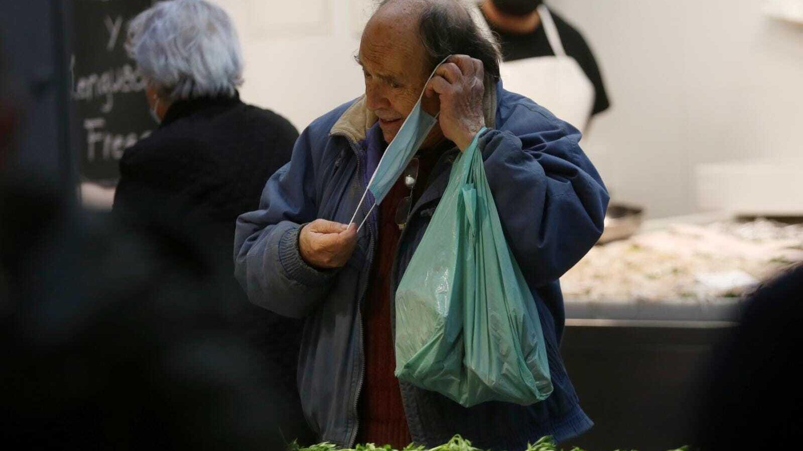 Un hombre se pone la mascarilla delante de un puesto de pescado, en Atarazanas.