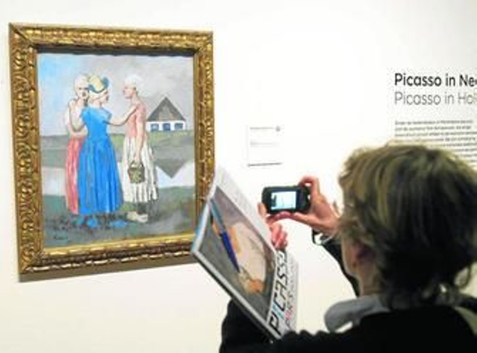 Una visitante al Museo Van Gogh fotografía 'Three Dutchs Girls', uno de los cuadros del genio malagueño que se puede ver estos días en una exposición.