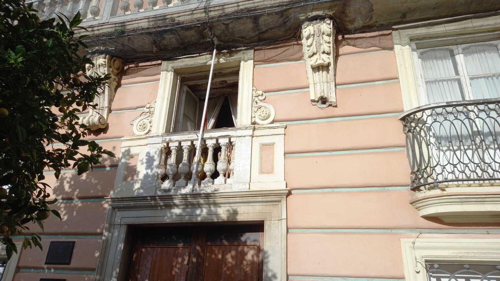 Ventana abierta en la primera planta del edificio, con el balcón de la segunda protegido por redes.