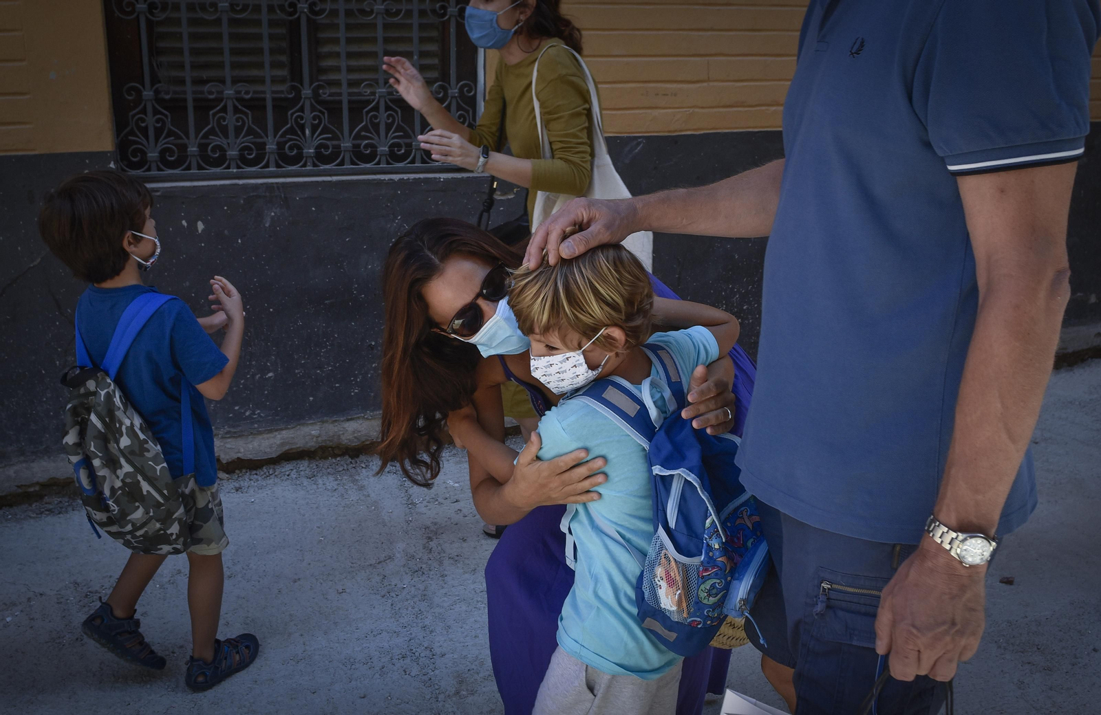 Una madre despide a su hijo en el primer día de clase.
