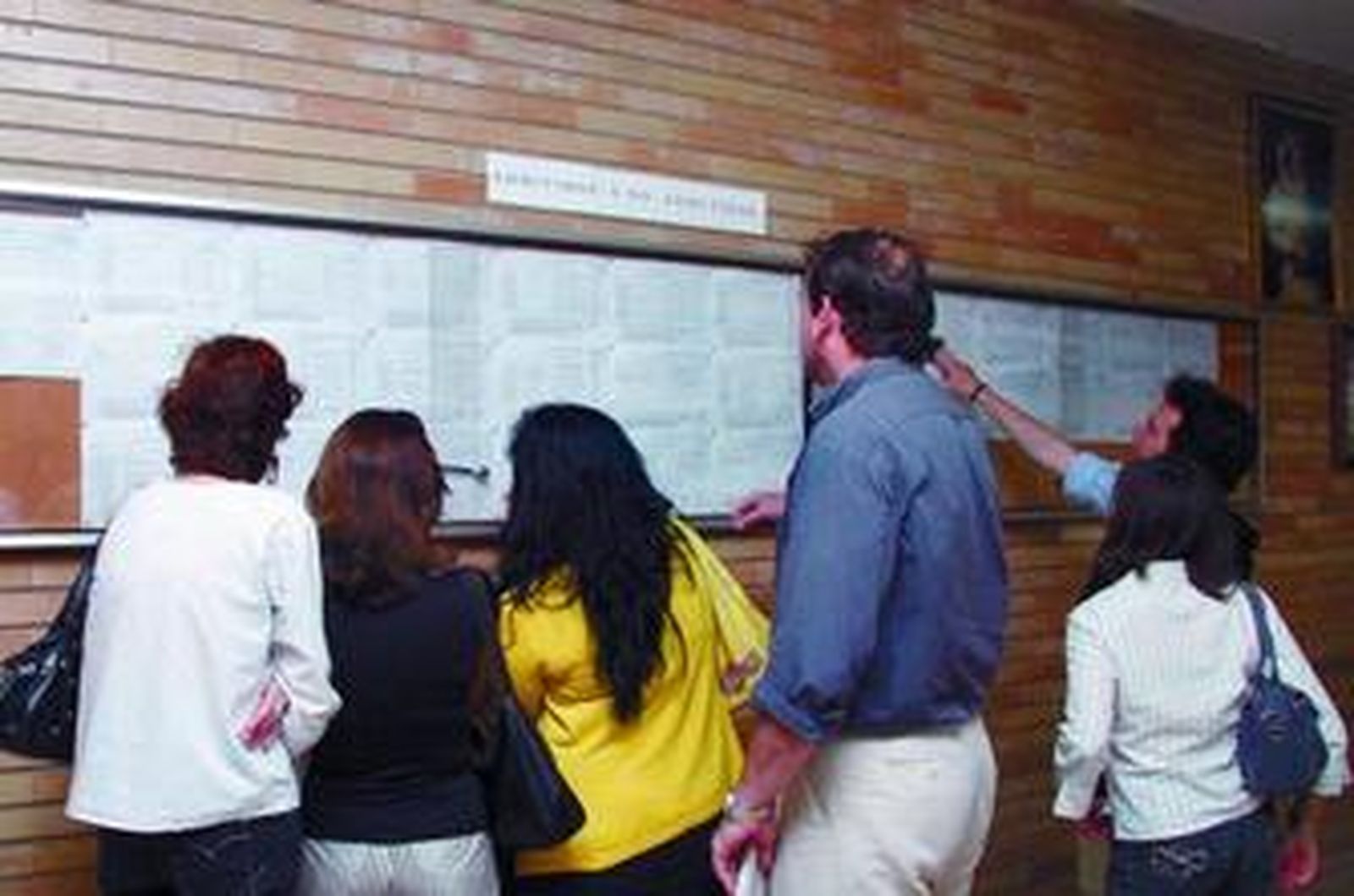 Varios padres buscan los nombres de sus hijos en las listas de Padres Blancos.