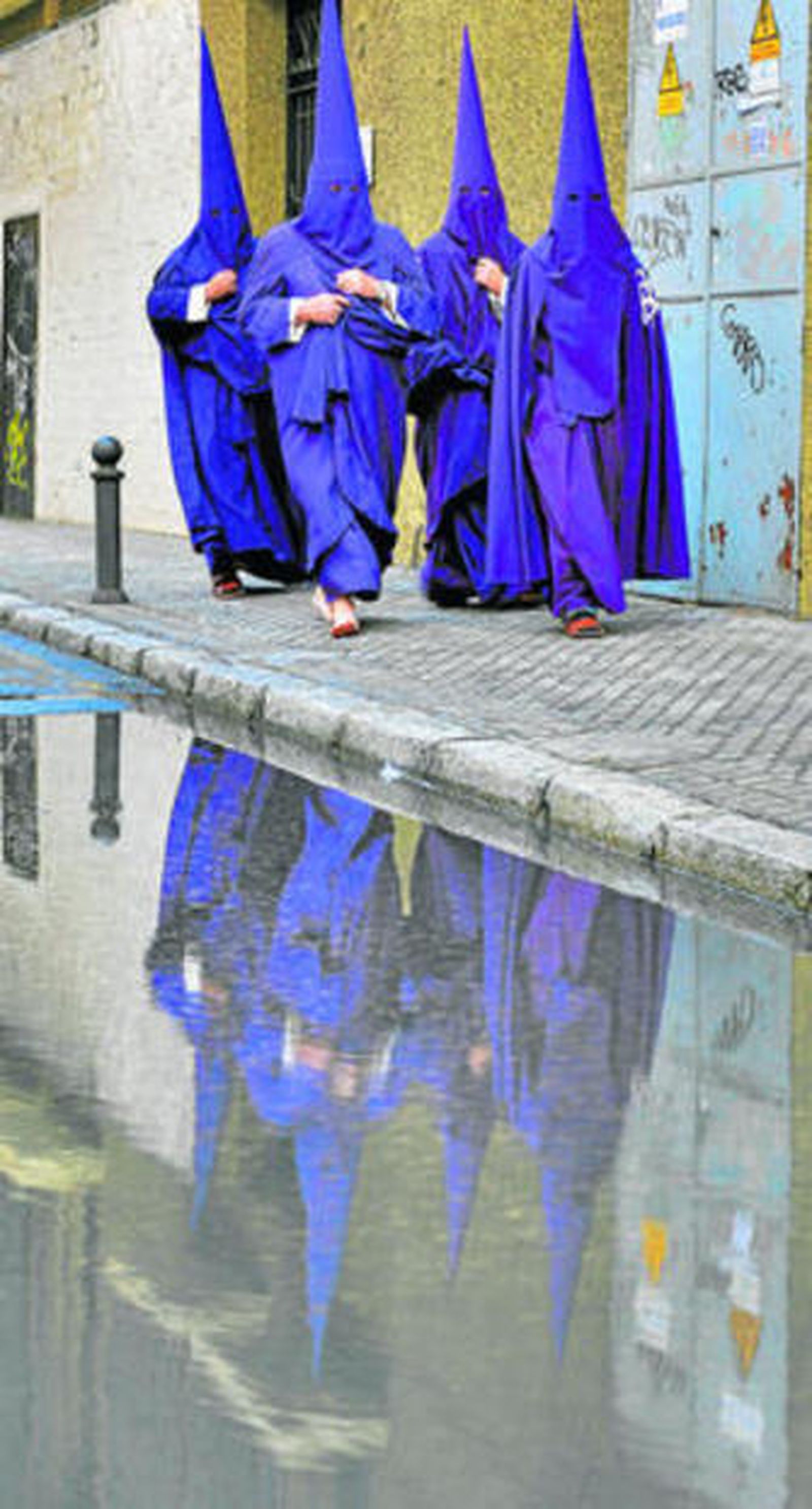 Nazarenos de la Quinta Angustia regresan a casa en una tarde de Jueves Santo lluviosa.