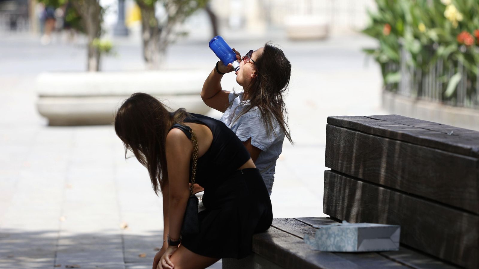 Dos jóvenes turistas, en los bancos a la sombra de la Puerta de Jerez.