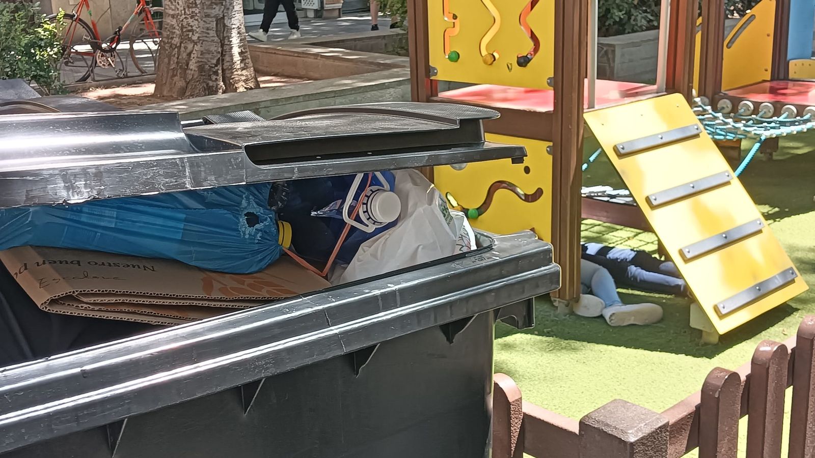 Un contenedor lleno de basura junto al lugar donde juegan los niños.