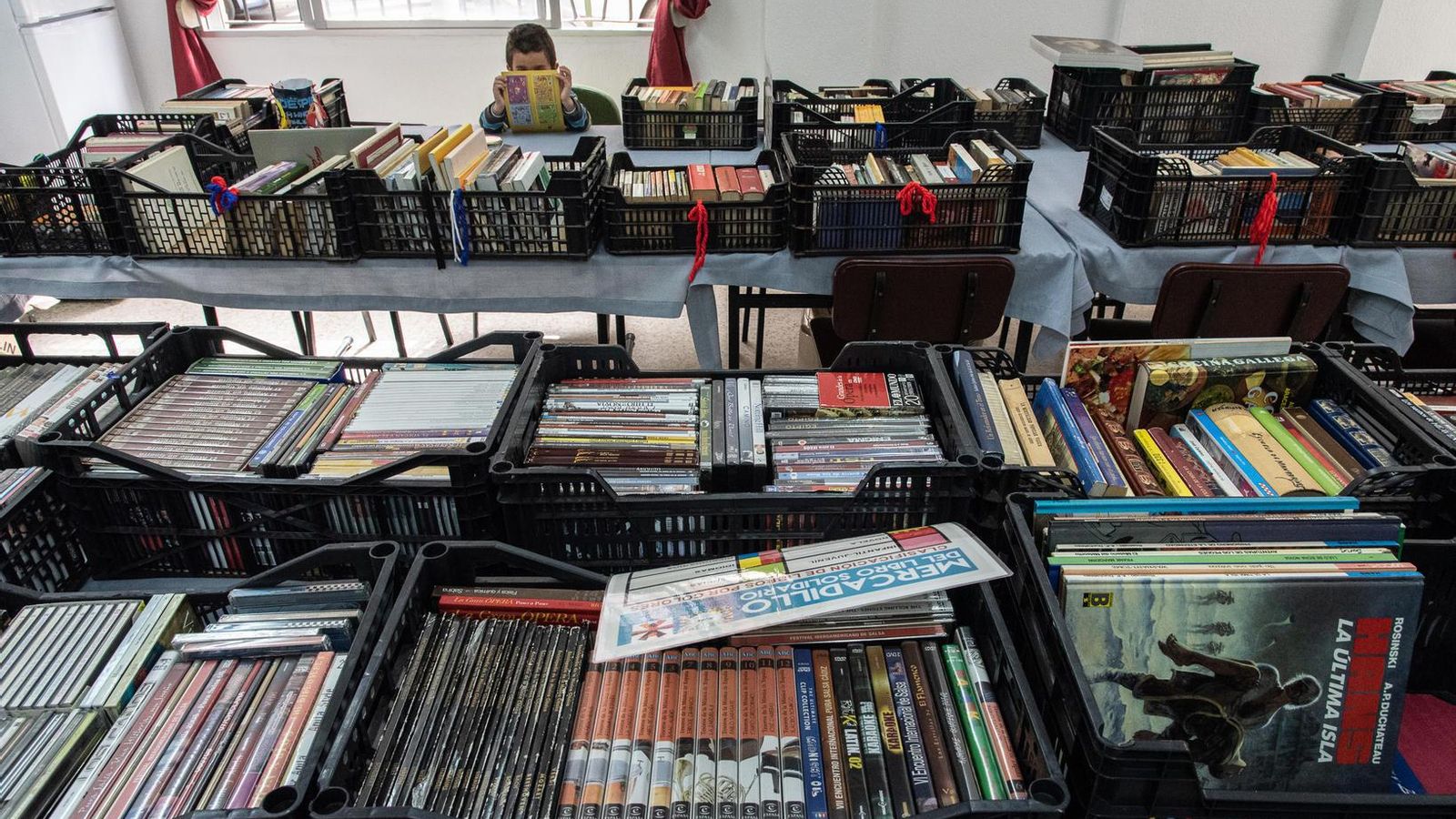 Un niño ojea uno de los libros en la librería de Ayre Solidario.