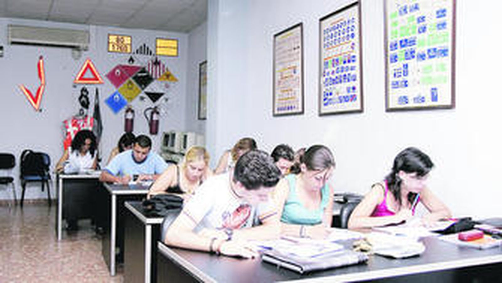 Un grupo de estudiantes se preparan para el exámen teórico en una autoescuela.