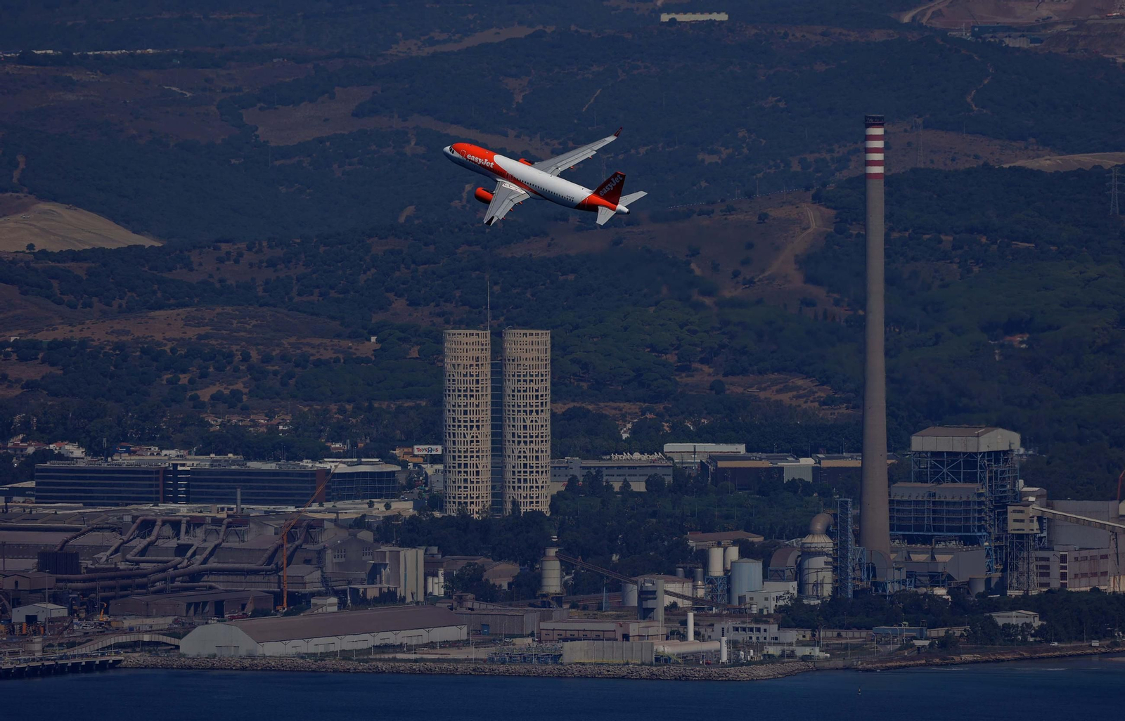 Un avión de pasajeros, el pasado martes, tras despegar desde el aeródromo de Gibraltar. Al fondo, las Torres de Hércules y la chimenea de la central térmica.