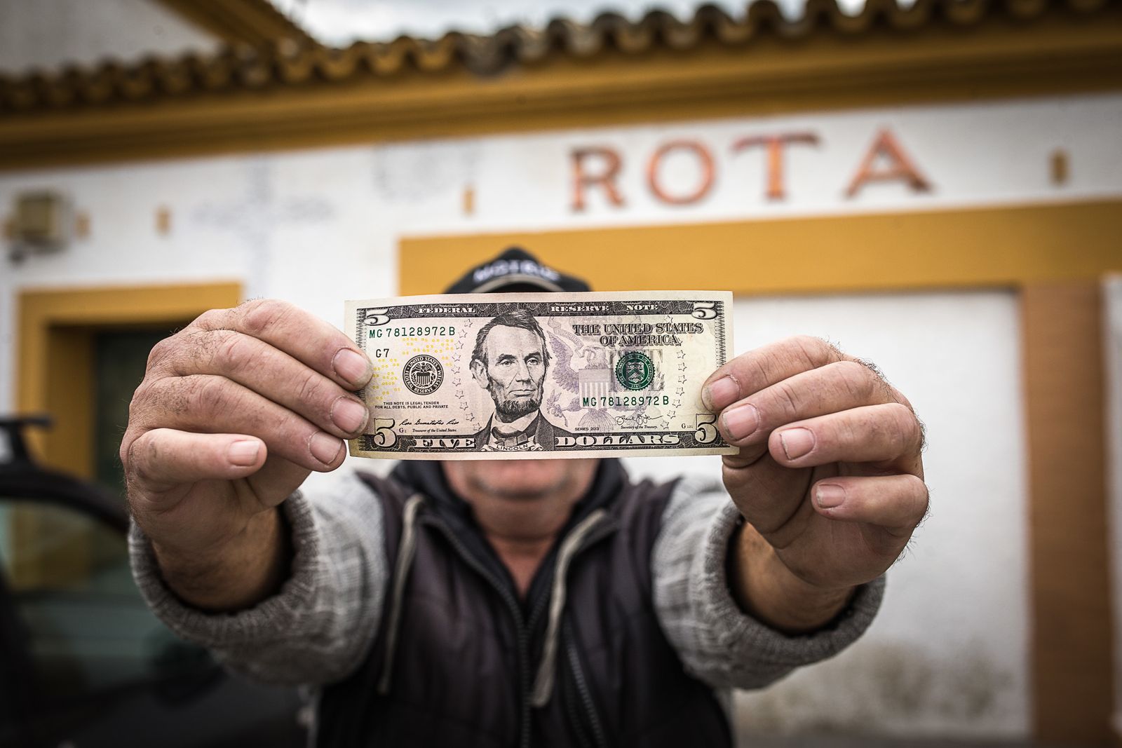 Un gorrilla posa ante la antigua estación de tren de Rota con un billete de dólar con la efigie del primer presidente republicano, Abraham Lincoln.  /Julio González