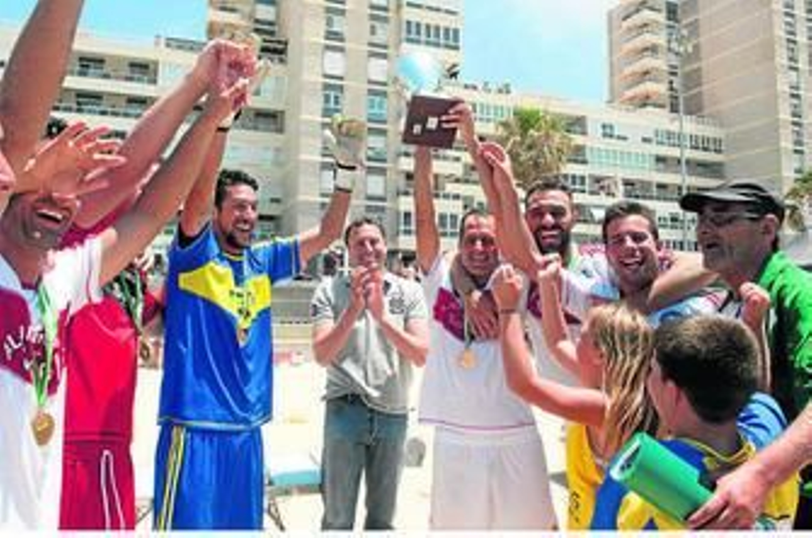 Los jugadores del equipo campeón celebran el título sobre la arena recién recibido el trofeo.