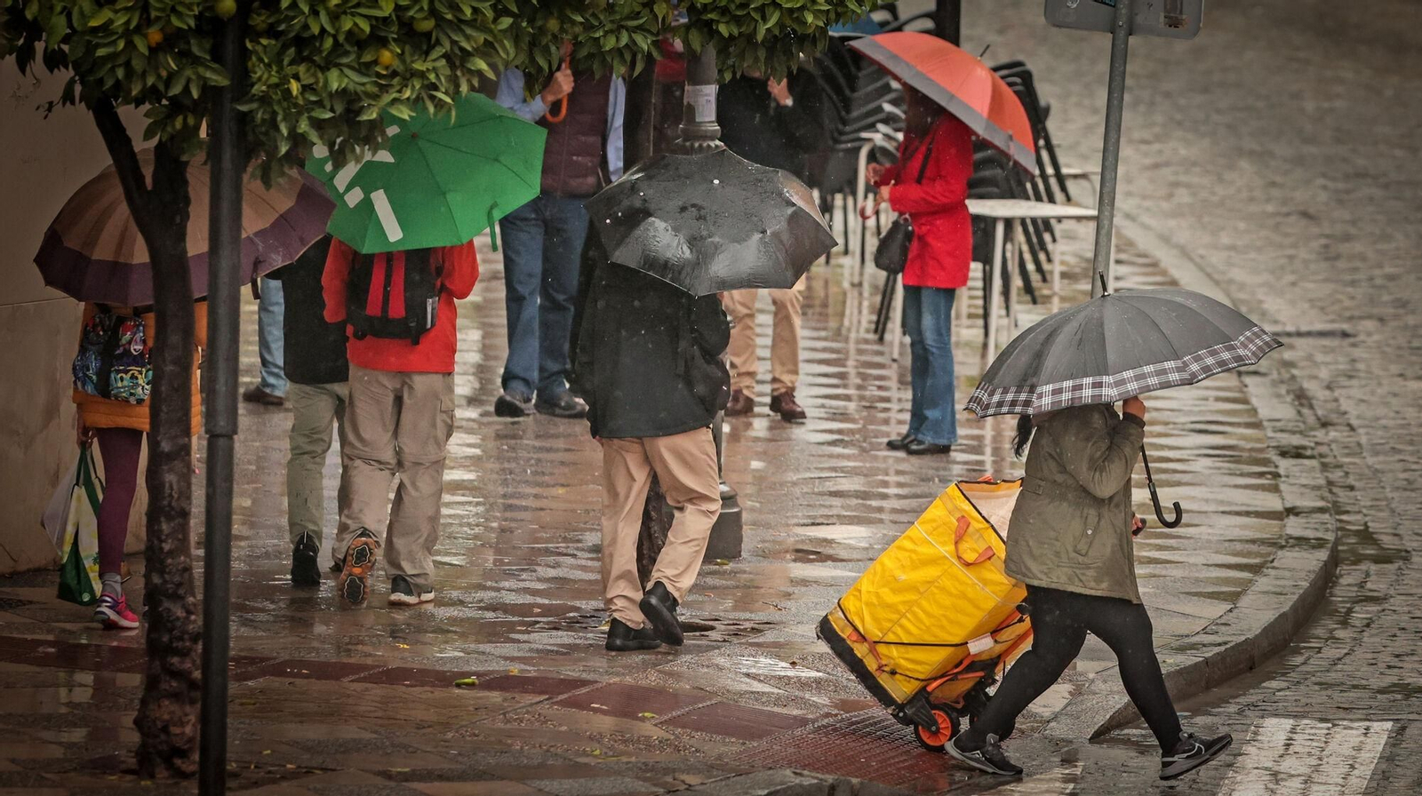 Varias personas caminando por la calle Larga mientras llueve