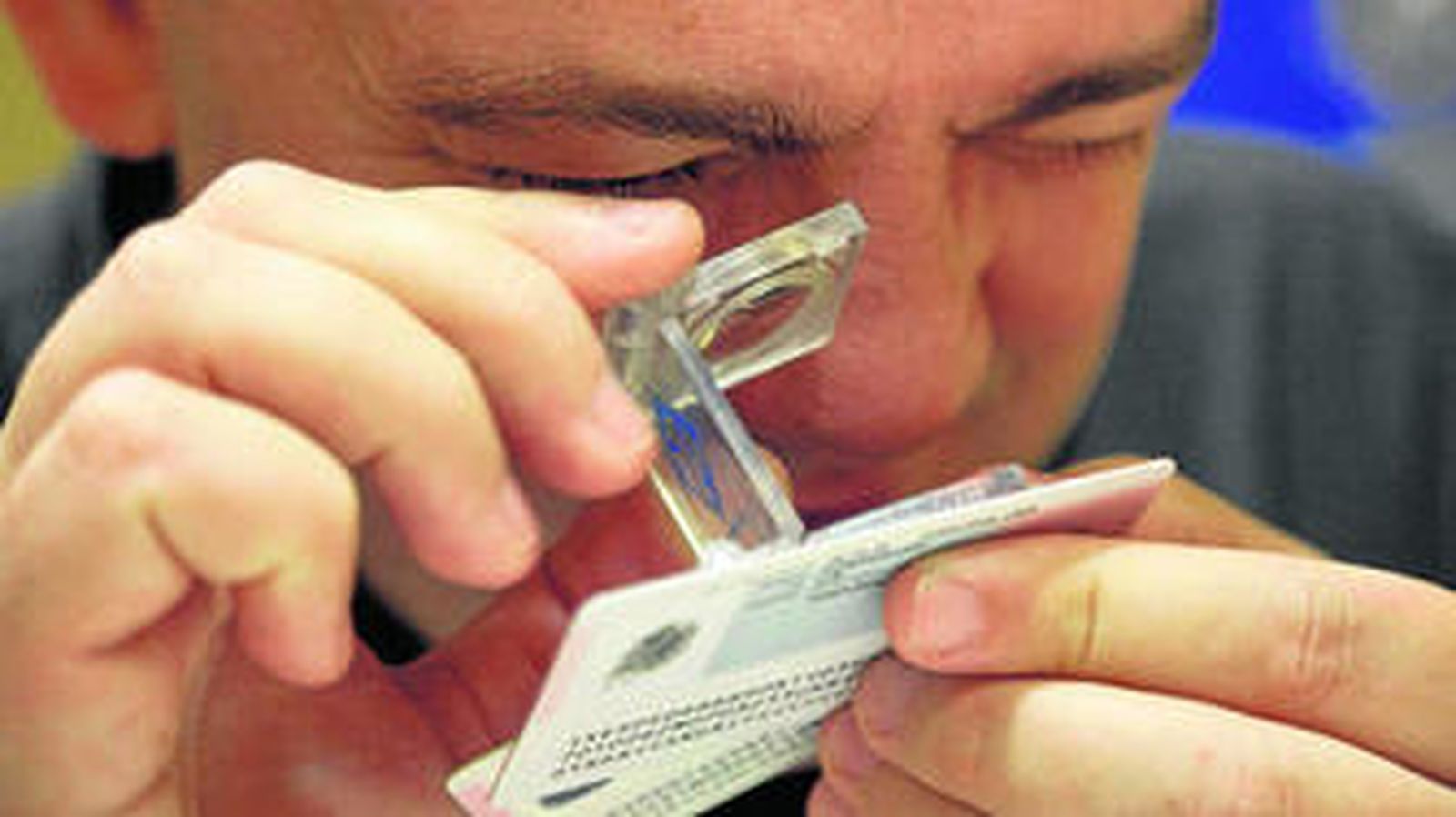 El policía Robert Sangil examina con una lente de aumento un carné.