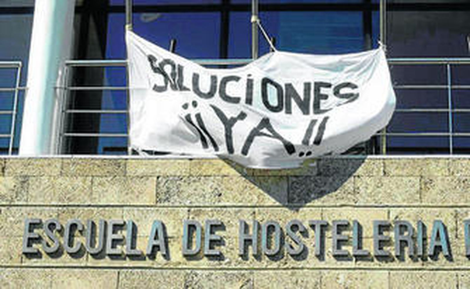 Una pancarta reclama una solución al impago de las nóminas en la fachada de la Escuela de Hostelería de Cádiz.