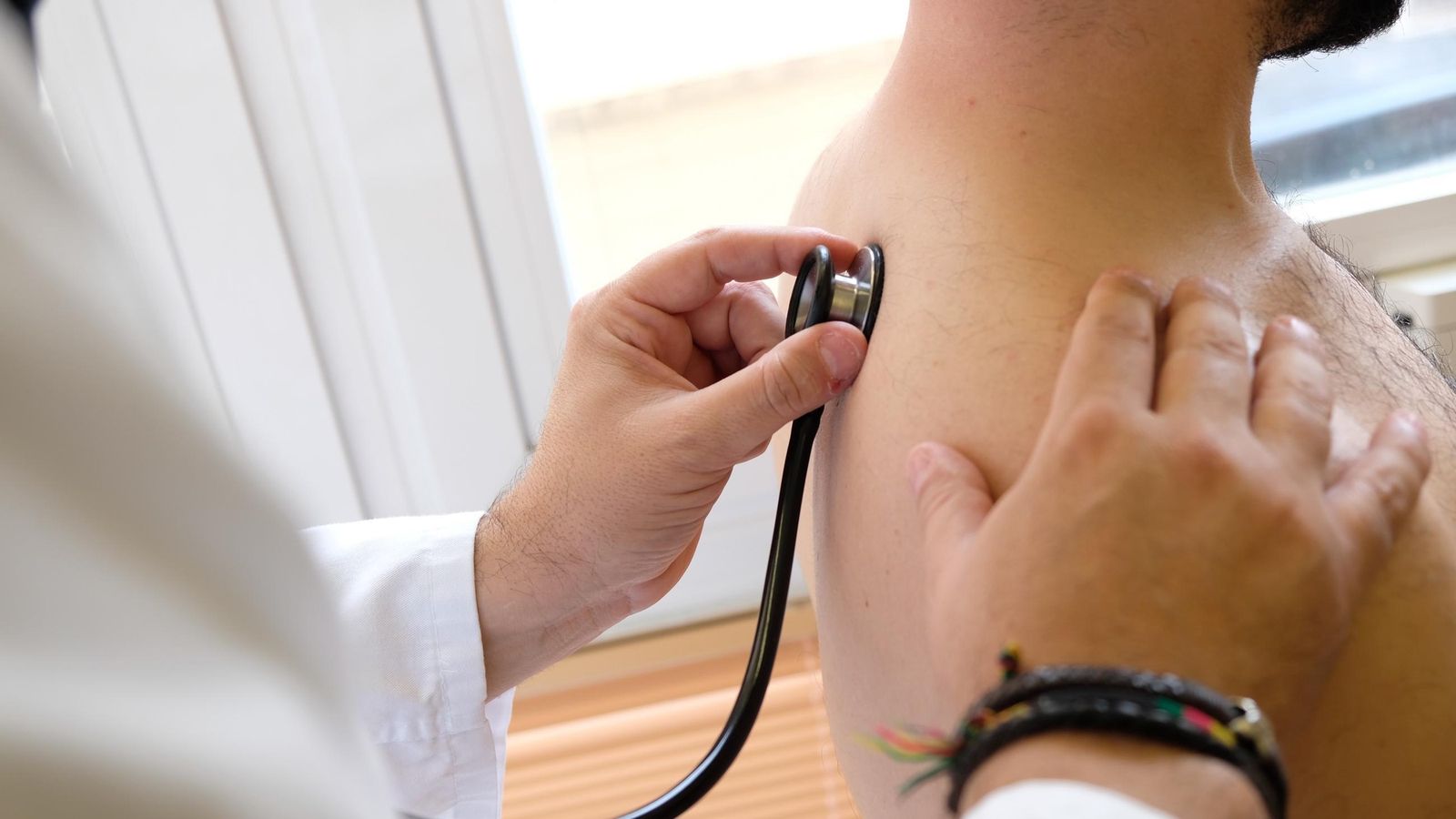 Un médico atiende a un paciente en consulta Un médico atiende a un paciente en consulta