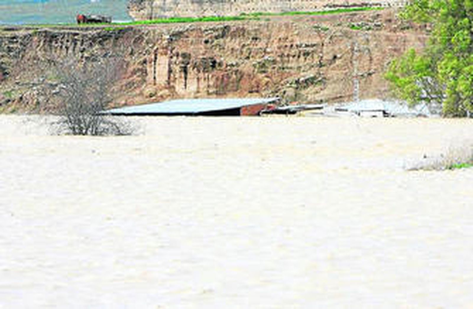El agua llegó ayer al techo de una nave agrícola de Lora del Río.