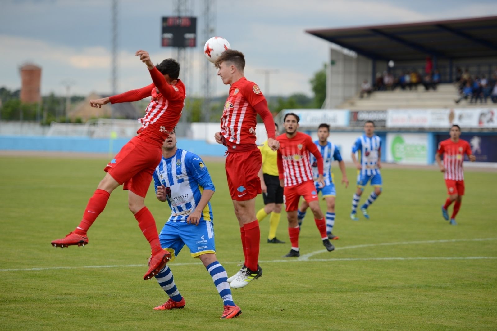 Dos jugadores rojiblancos saltan para despejar un balón aéreo durante el partido en El Montecillo.