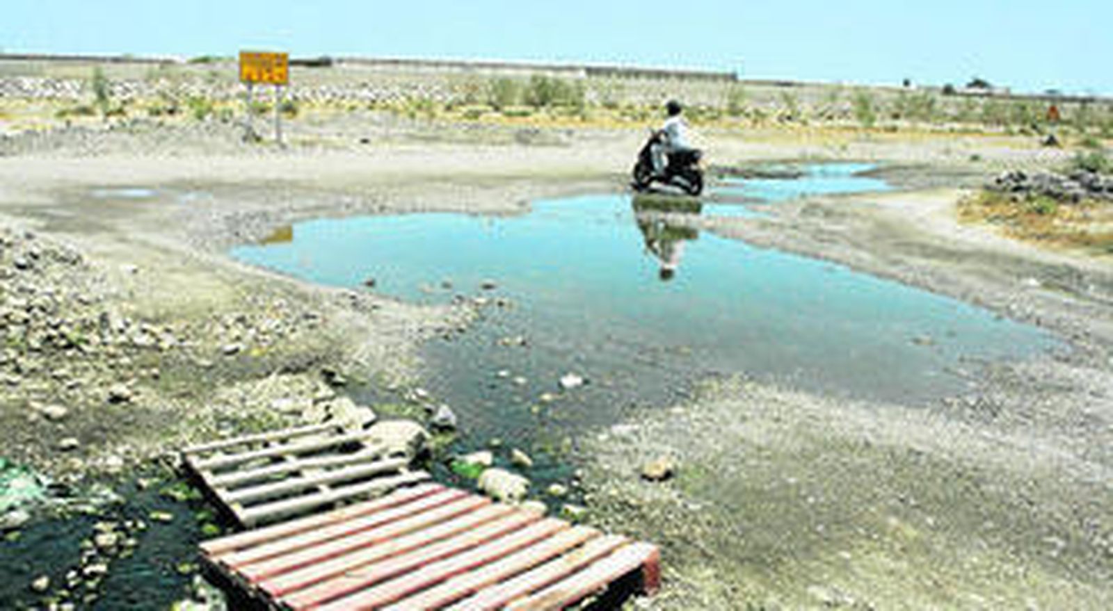 El conductor de un ciclomotor sortea como puede unas aguas claramente contaminadas.