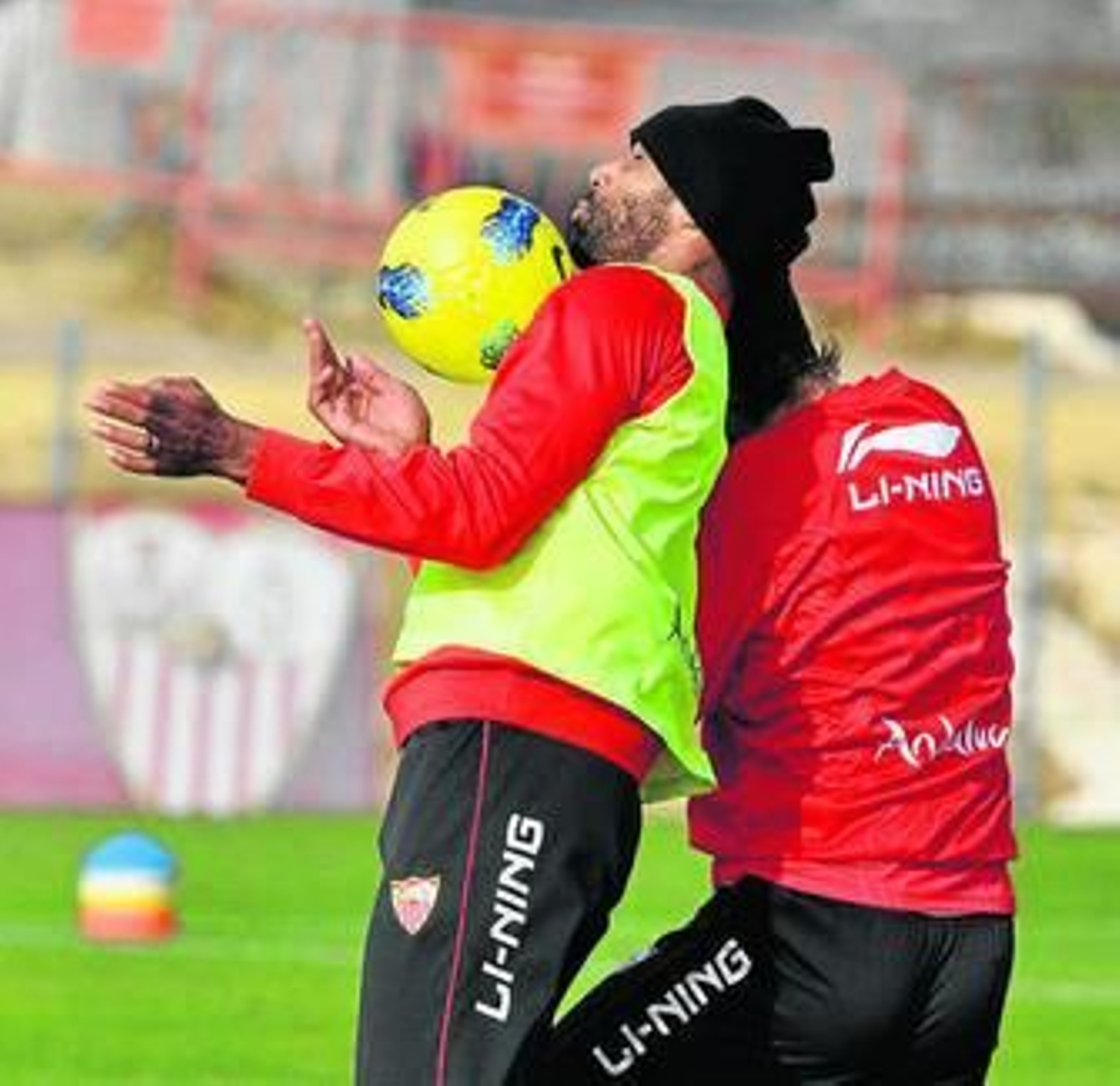 Kanoute para un balón con el pecho presionado por un defensa.