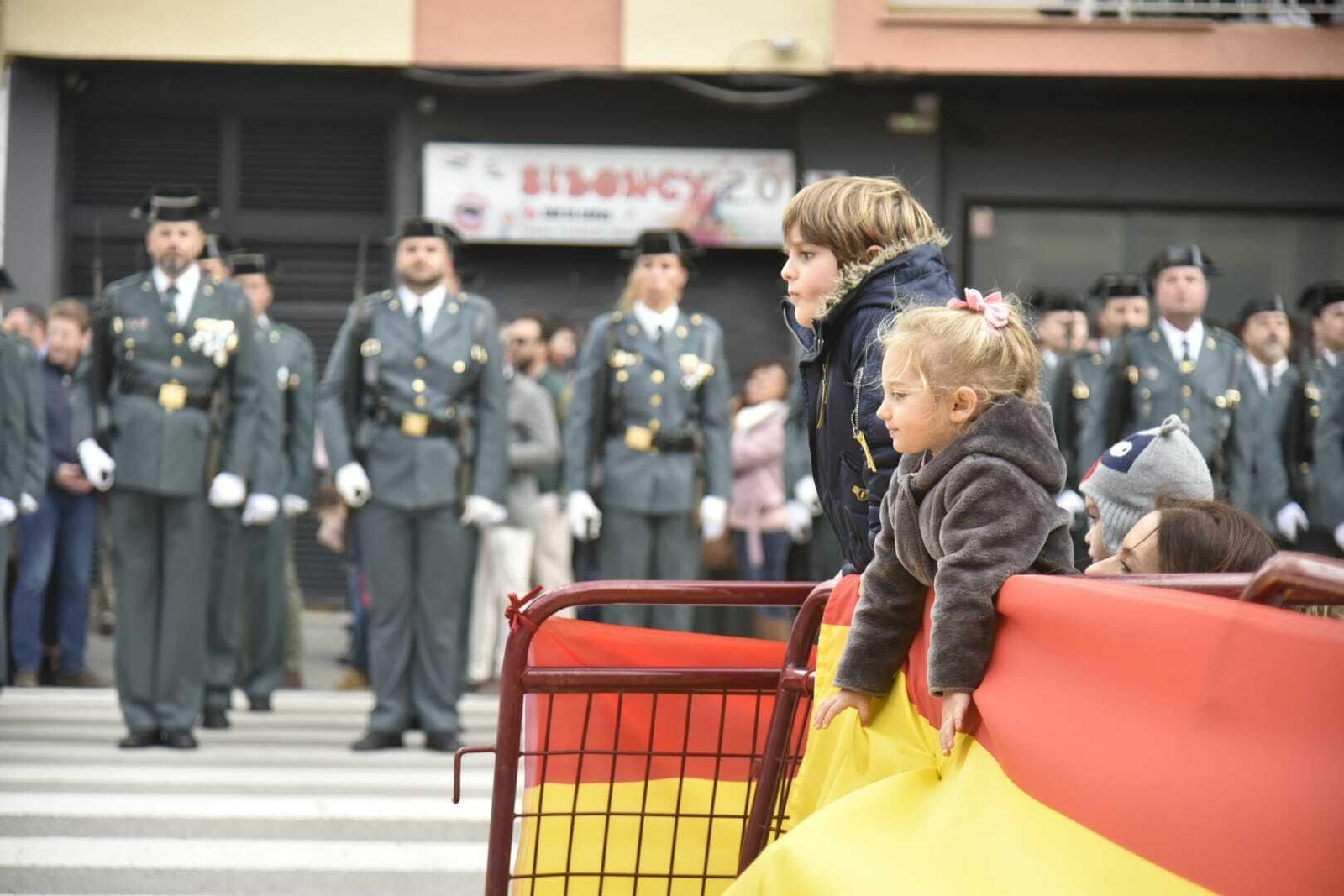 Dos niños siguen los actos de la jura de bandera civil delante de una formación.