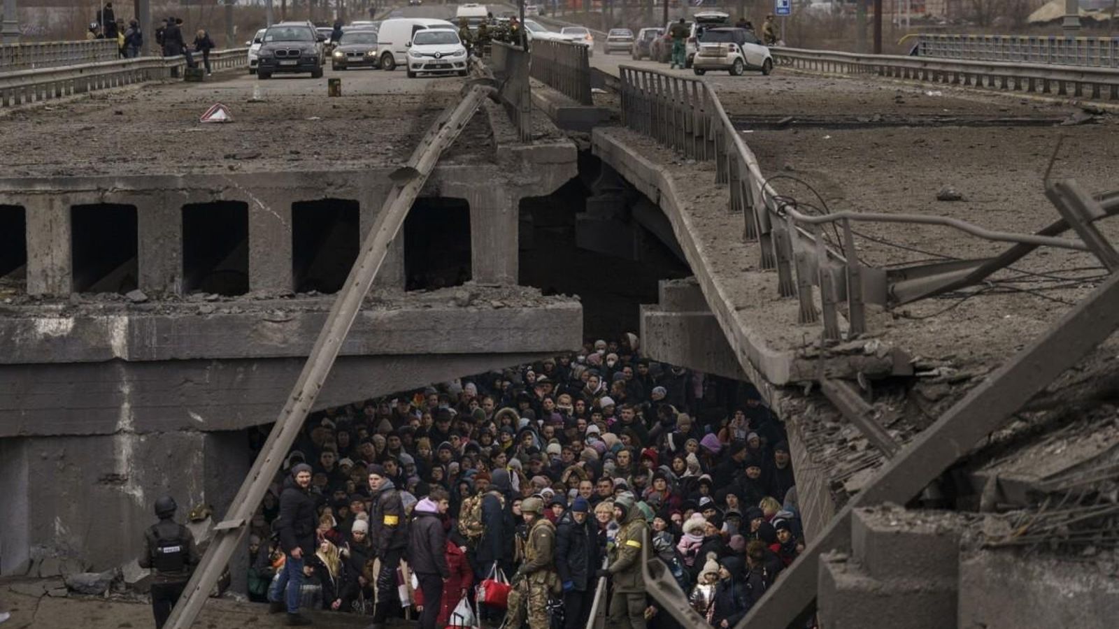 Los ucranianos se amontonan debajo de un puente destruido mientras intentan huir cruzando el río Irpin en las afueras de Kiev, Ucrania, el sábado 5 de marzo de 2022. (Foto de Emilio Morenatti).