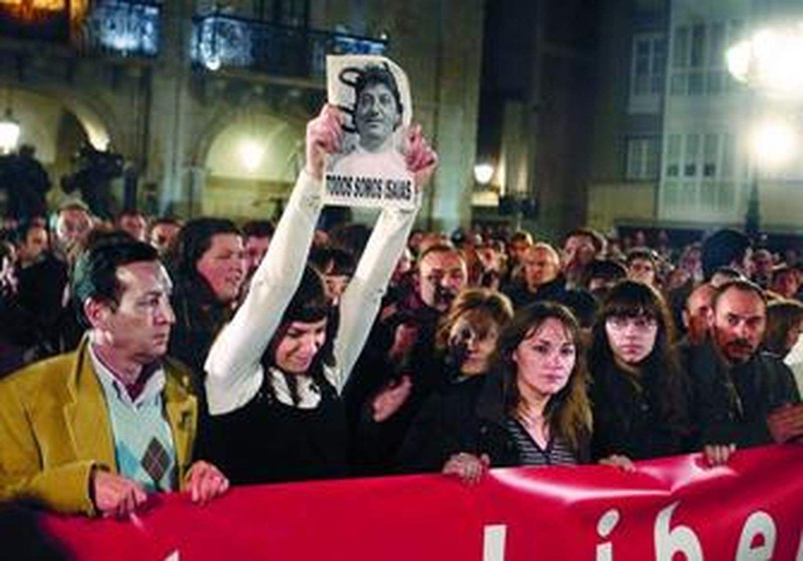 Sandra Carrasco enarbola una foto de su padre durante la manifestación de anoche. A su lado, su madre, su hermana Ainara y otros familiares.