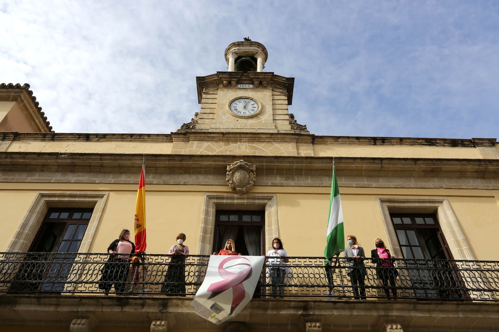 Rocío Sánchez, Carmen Collado, Conchi Fernández y María José López, en el balcón del Ayuntamiento junto a la alcaldesa y el lazo rosa.