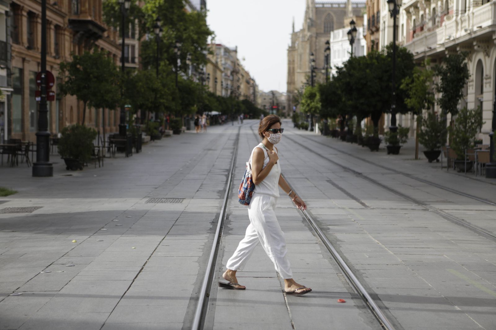 Una mujer cruza una solitaria Avenida de la Constitución.