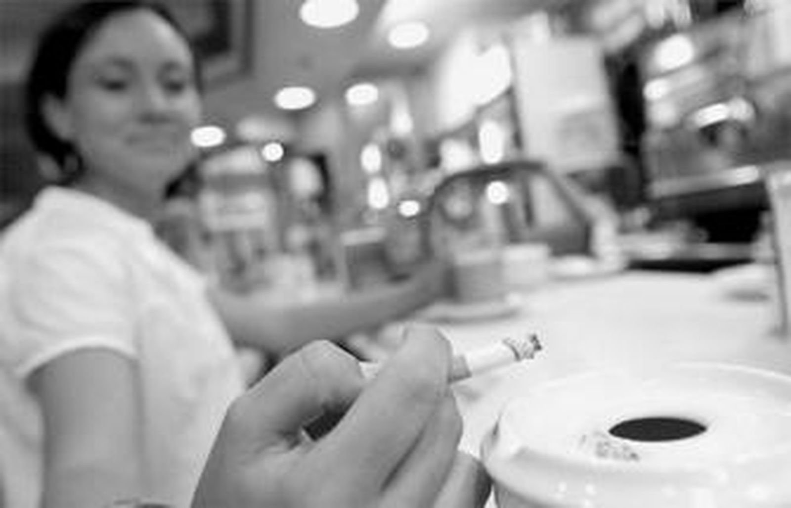 Una mujer fuma en una cafetería.