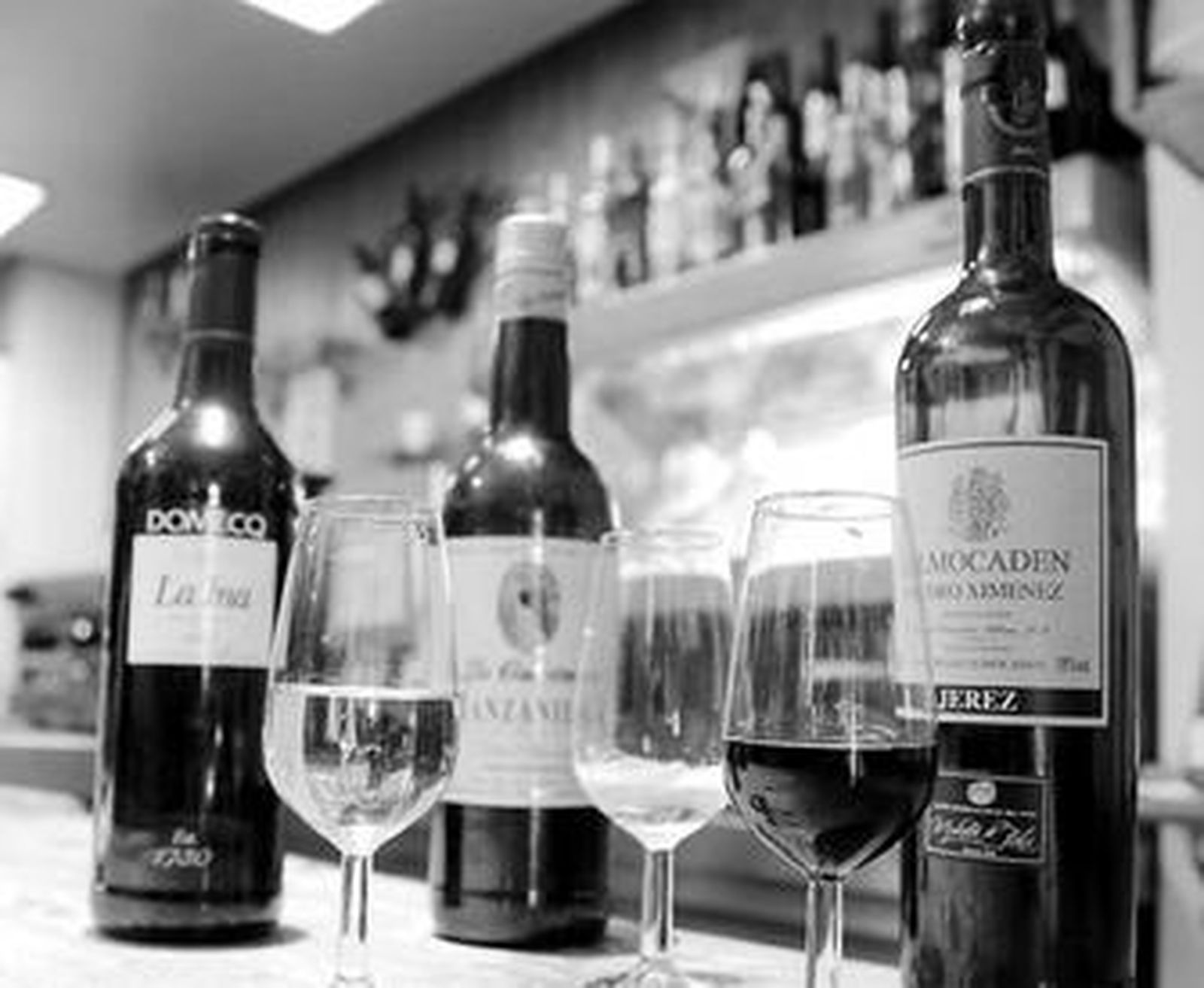 Bodegón con botellas y copas de fino, manzanilla y Pedro Ximénez en un bar de Jerez.