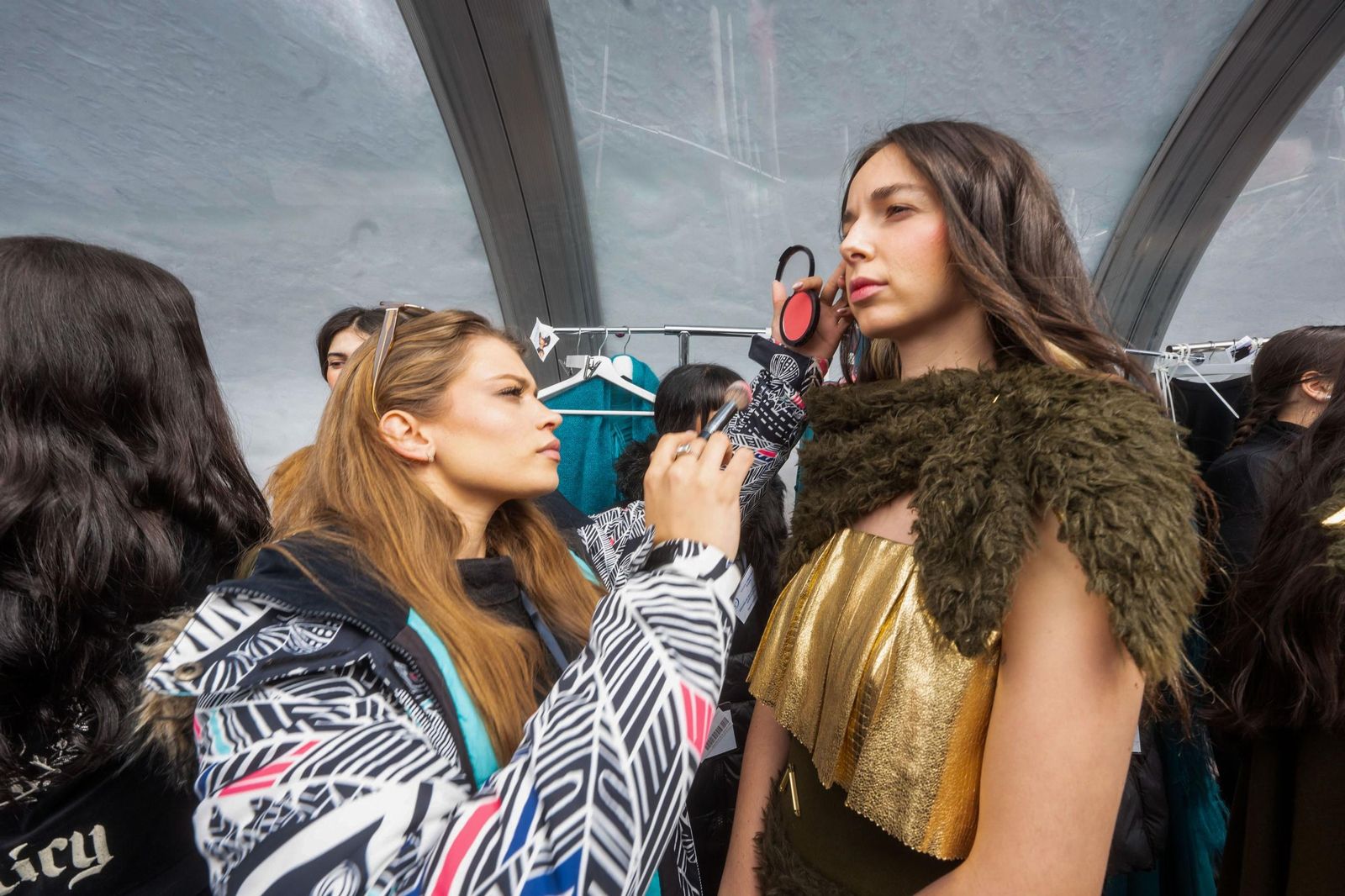 Una maquilladora dando los últimos retoques a una modelo.