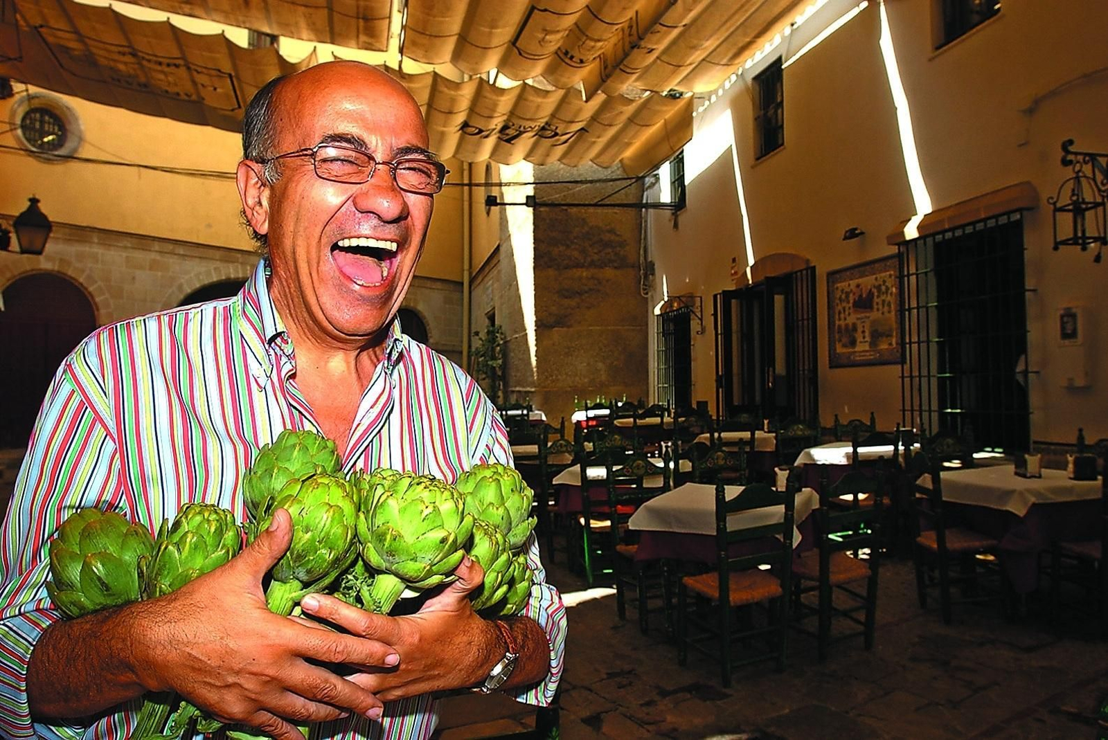 Faustino Rodríguez, Fau, suelta una de sus inconfundibles carcajadas con un puñado de alcachofas, principal seña de identidad del Bar Juanito.